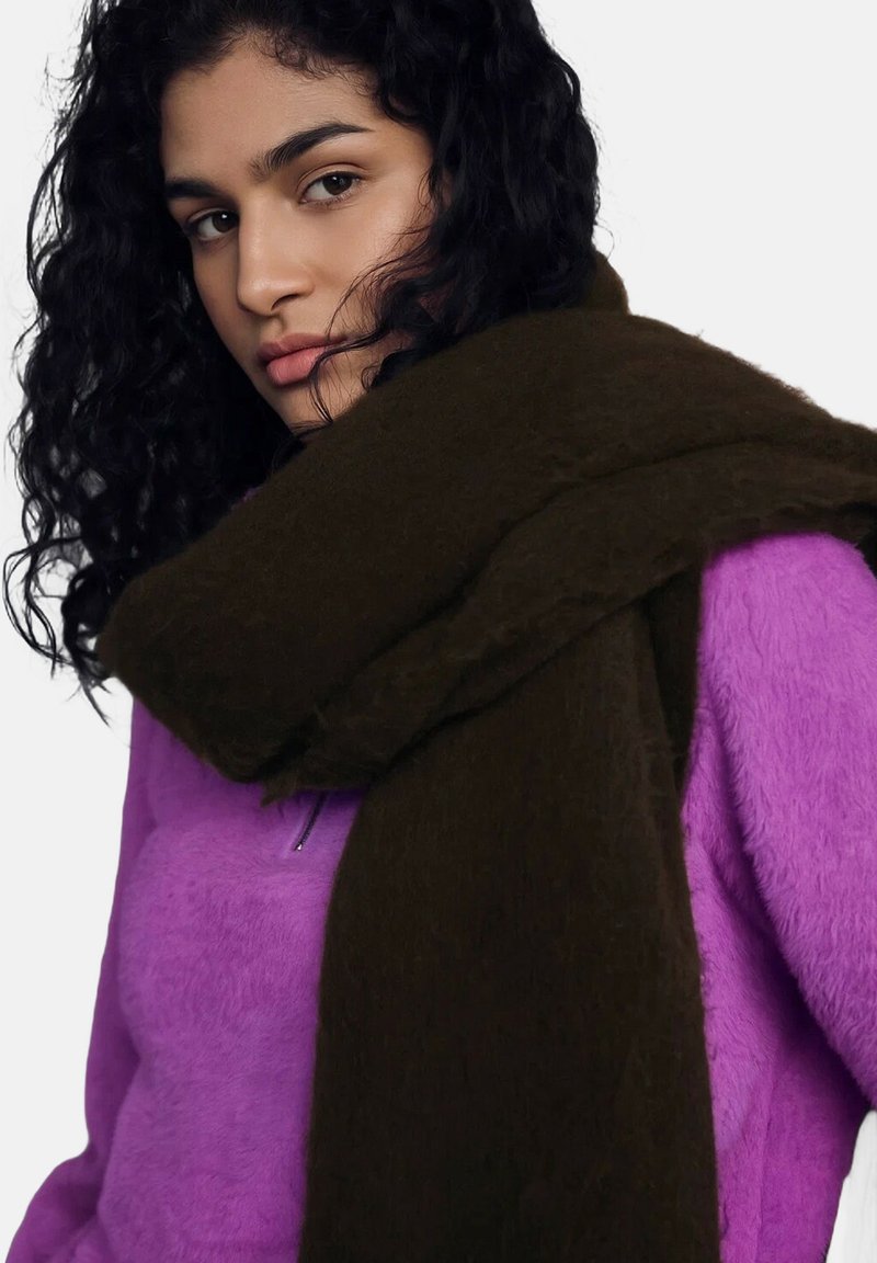 Sciarpa di lana marrone drappeggiata su una maglia in pile viola. La sciarpa ha un aspetto morbido e texturizzato, mentre il pile è soffice e vivace.
