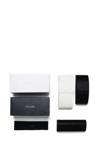 Due scatole rettangolari, una bianca e una nera, con superficie testurizzata e il logo "PRADA" in rilievo. Include un panno pulente nero e due custodie.