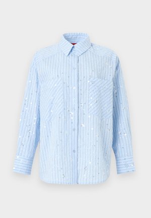 Ανοιχτό μπλε πουκάμισο με λεπτές κάθετες ρίγες και διασκορπισμένες ασημί παγιέτες, με δύο τσέπες στο στήθος και μακριά μανίκια με μανσέτες με κουμπιά.