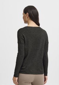 Pull vert foncé en tricot doux, doté de manches longues et d'une coupe décontractée. Le dos a une encolure arrondie et un design simple.
