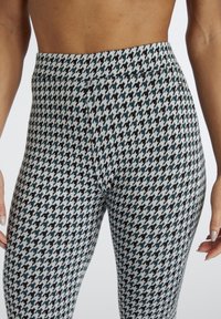 Leggins u uzorku ptičjeg zuba sa crnom i plavom bojom na svijetloj podlozi, s prilagođenim oblikom i elastičnom gumom u struku. Raztegnuta tkanina.