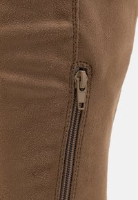 Brune faux-suede støvlett med sidelukking, med en teksturert overflate og kontrasterende sømmer langs glidelåsområdet.