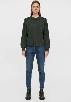 Maglione pullover grigio scuro con collo rotondo, maniche lunghe e dettagli con bottoni sulle spalle, abbinato a jeans skinny blu e stivaletti neri.