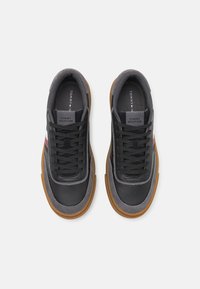 Baskets noires et grises en cuir et daim, avec des semelles en caoutchouc gomme, des accents texturés et un logo sur la languette.