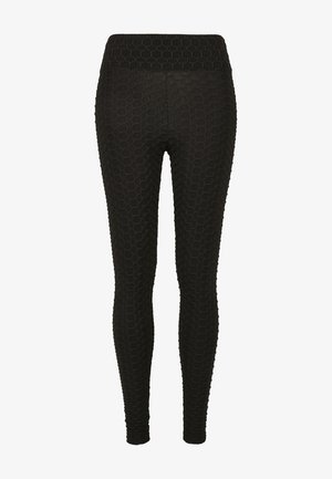 Černé legíny s texturovaným vzorem připomínající včelí plástve, s širokým pasem. Vyrobené z elastického materiálu, navržené pro těsné přilnutí.