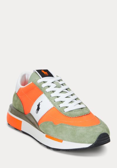 Zema sporta kurpe ar zaļu zamšādas apdari, spilgti oranžām daļām, baltām mežģīnēm, melnu zirga logo uz sāna un baltu zoli ar oranžiem akcentiem.