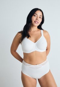 White bra with underwire cups and wide straps paired with high-waisted white panties featuring sheer accents. Smooth, stretch fabric.