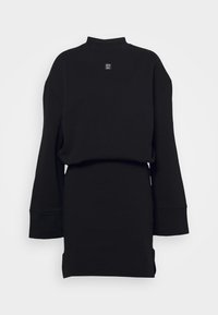 Mini-robe noire à manches longues avec un haut ample et une jupe ajustée, avec un petit logo carré au centre de la poitrine.