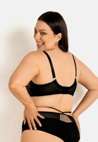 Czarny zestaw bielizny składający się z biustonosza z przezroczystą koronkową plecami, z regulowanymi ramiączkami oraz dopasowanych majtek z siateczkowymi akcentami i teksturowanym wzorem.