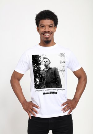 Bílý bavlněný tričko s černobílým potiskem postavy v masce, s textem níže, který říká "Každý má právo na jeden dobrý strach."