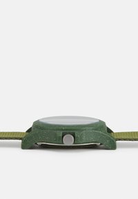 Grün Uhr mit einem strukturierten Kunststoffgehäuse und einer silbernen Krone. Sie verfügt über ein grünes Textilarmband, das ein minimalistisches Design betont.