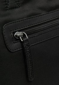 Materiale in nylon nero con finitura testurizzata, dotato di chiusura con zip e dettagli in pelle. Include un'etichetta impresso con "The Chesterfield Brand."