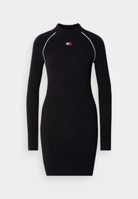 Μαύρο πλεκτό φόρεμα με μακριά μανίκια και ψηλό λαιμό, με αντίθετες λευκές ραφές και μικρή λεπτομέρεια λογότυπου στο στήθος.