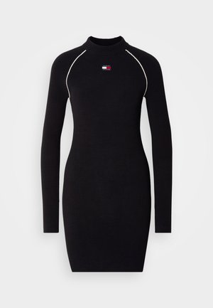 Black ribbed long-sleeve dress with a high neckline, featuring contrasting white stitching and a small logo detail on the chest.