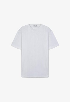 T-shirt bianca a maniche corte con scollatura a girocollo e un delicato motivo a chevron verticale, adagiata su uno sfondo bianco.