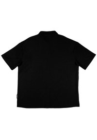 Black short-sleeve polo shirt, plain design, collared with a straight cut, featuring a small label detail at the hem.