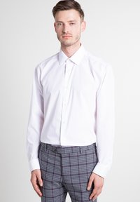 Witte blouse met lange mouwen, een formele kraag, een knoopsluiting en een zachte katoenstructuur. Gecombineerd met een broek met een geruit patroon.