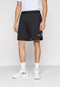 Črne športne hlače iz zračnega materiala z elastičnim pasom, z logotipom in trim barvnim poudarkom blizu roba.