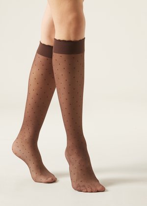 Brune polka dot knæhøje strømper med en gennemsigtig tekstur og rynket topkant, der har et mønster af små prikker over hele.