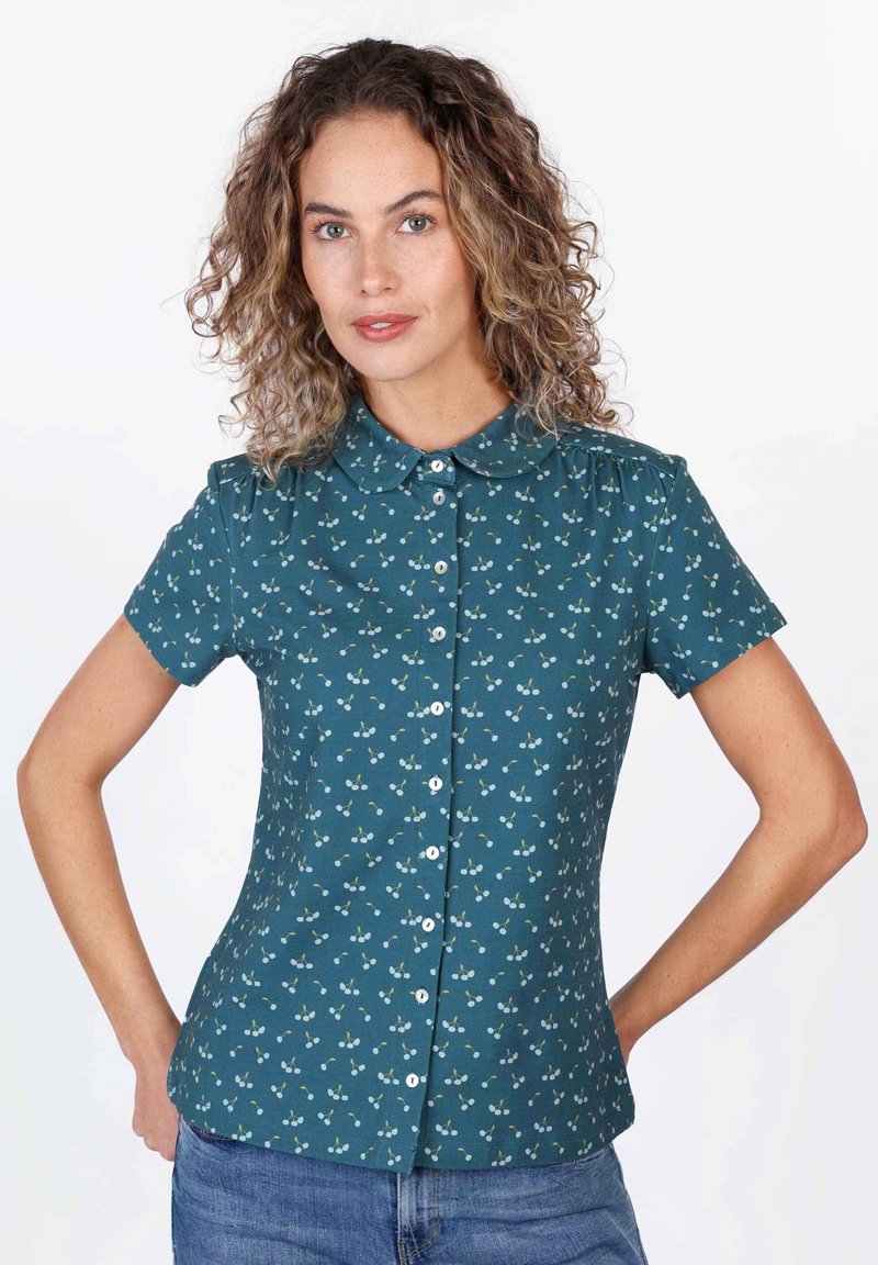 Teal short-sleeve blouse with a collared neckline, featuring a floral pattern in light colors and front button closure. Smooth texture.