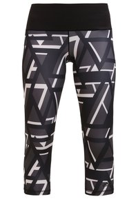 Leggings capri à motifs noir et blanc avec une large ceinture, présentant des formes géométriques et une texture de tissu lisse et extensible.