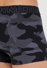 Bóxer ajustado para hombres en negro y gris con un tejido transpirable y elástico. Cuenta con una cinturilla gruesa con el logo "ARMOUR".