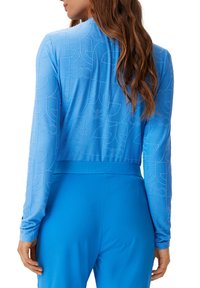 Maglietta blu a maniche lunghe con un motivo testurizzato e una vita con logo. Realizzata in tessuto liscio con un design aderente.