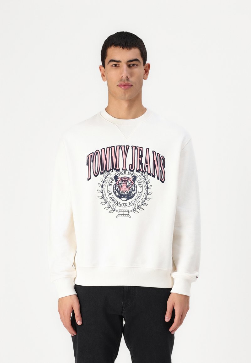 Witte sweatshirt met een groot "TOMMY JEANS" logo in rood en blauw, een gecentreerd beeld van een tijger, en geribbelde manchetten en zoom.