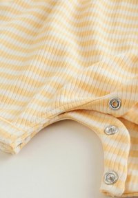 Tessuto a righe gialle e bianche che mostra una morbida trama a coste con chiusure a scatto in metallo ai bordi del collo.