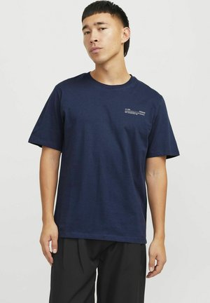 Camiseta de algodón azul marino con mangas cortas, cuello redondo y un pequeño detalle impreso en blanco en el pecho. Textura suave y ajuste relajado.