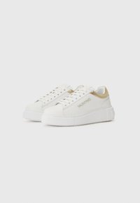 Hvite lær sneakers med en jevn tekstur, gullfarget detaljer, flat hvit såle, rund tå og merkevaredetalj på siden.