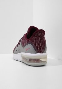 Baskets Nike Air Max avec une tige en maille bordeaux, une semelle intermédiaire grise, un amorti air transparent, une semelle blanche et des accents de logo roses.