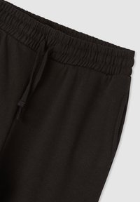 Pantaloni della tuta neri con vita elastica e coulisse, dotati di tasche laterali e tessuto morbido e strutturato.