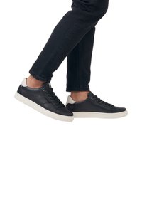 Schwarze Ledersneaker mit einer weißen Gummisohle, entworfen mit einer glatten Oberfläche, runder Zehenpartie und kontrastierender Fersenakzentuierung.