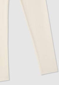 Jasno kremowe legginsy wykonane z miękkiego, elastycznego materiału. Charakteryzują się gładką teksturą, dopasowanym krojem i minimalnymi detalami szwów.