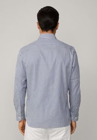Striped shirt in blue and white, cotton fabric, buttoned cuffs, back view with a tailored fit and a classic collar design.