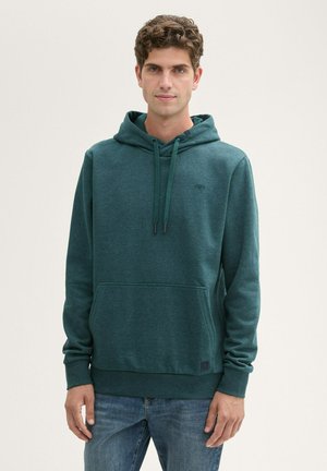 Groene hoodie van een zachte, gestructureerde stof met een voorzak en verstelbare koordjes, gedragen met blauwe denim jeans.