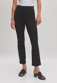 Schwarze maßgeschneiderte Hose mit weitem Bein, aus glattem Material und mittelhohem Bund. Mit einer dezenten Vorderasche akzentuiert.