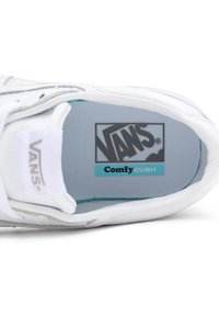 Vue de dessus d'une sneaker blanche Vans montrant une semelle intérieure bleu clair étiquetée "ComfyCush" et le logo Vans sur la languette et la semelle intérieure.