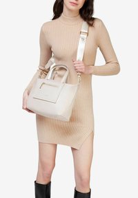 Beige håndtaske lavet af struktureret materiale, med en rektangulær form, topgreb og en aftagelig rem. Indeholder en frontlomme med lynlås.