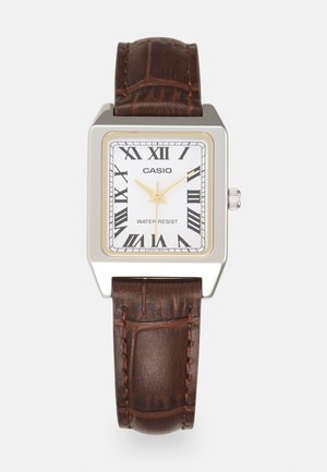 Casio rectangular watch with a white face, gold accents, Roman numerals, and a brown crocodile-pattern leather strap. Water-resistant design.