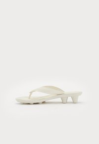 White low-heeled flip-flop sandal with wide straps and textured sole, displayed on a plain white background.