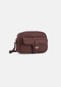Borsa a tracolla in pelle marrone con texture, dotata di una chiusura con patta anteriore e hardware in tono oro, caratterizzata da un piccolo logo. Design compatto.