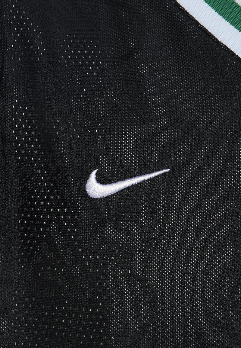 Tissu de sport noir avec un motif texturé ; présente un logo Nike en broderie blanche sur le côté gauche. Les accents incluent des rayures vertes et blanches.