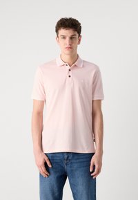 Πόλο μπλούζα σε απαλό ροζ βαμβάκι, με κλασικό γιακά, τρεις κουμπιά και λεπτομέρεια λογότυπου στο αριστερό στήθος. Κοντό μανίκι.