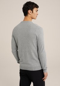 Suéter de manga larga gris claro hecho de suave tejido de punto, con cuello redondo, puños acanalados y una silueta ajustada.