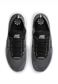 Czarno-szare sneakersy Nike Free charakteryzują się dzianą cholewką, zaokrąglonym czubkiem, białą podeszwą środkową oraz czarnymi sznurówkami z wyraźnym logo na języku.