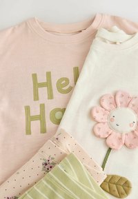 Négy póló: egy rózsaszín zöld "Hello" felirattal, egy krémszínű rózsaszín virágmintával, és két minta virágos és csíkos témában.