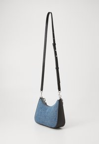 Axelväska i denim och svart läder med en böjd form, silverdetaljer, justerbar rem och dragkedja. Texturerade ytdetaljer.