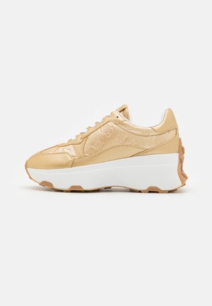 Sneaker dorato con tomaia texturizzata, suola intermedia bianca e suola esterna in gomma marrone. Caratterizzato da lacci rotondi e un design del tallone leggermente rialzato.